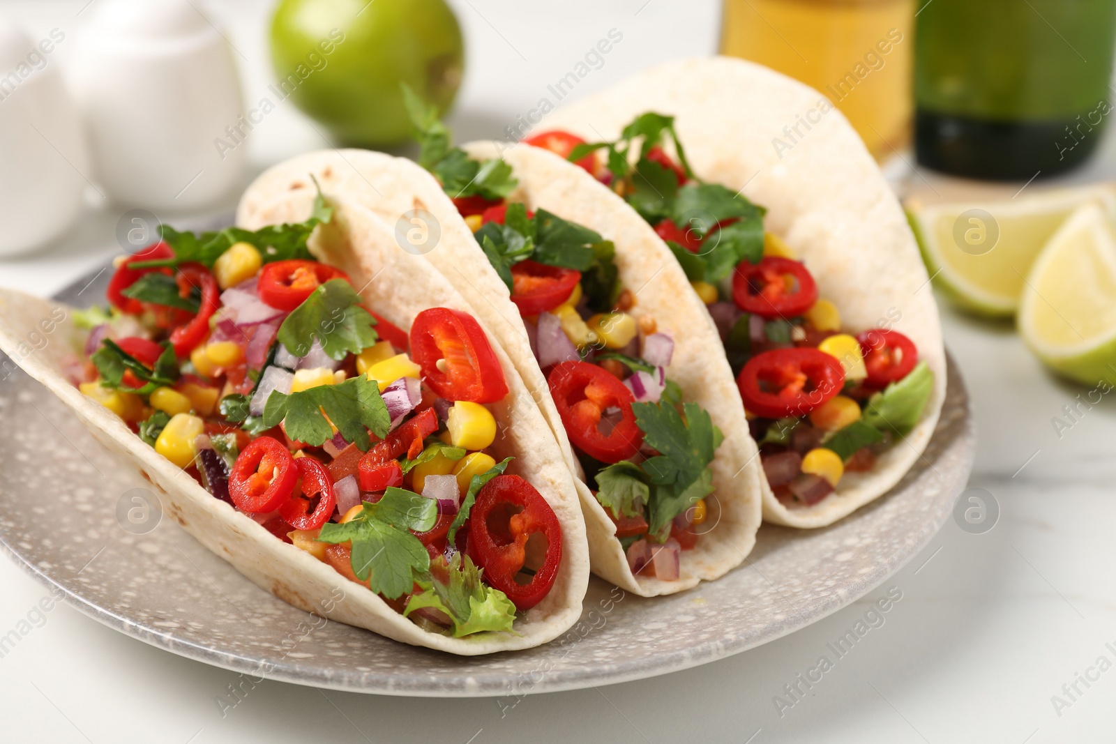 Photo of Tasty tacos with vegetables on white marble table, closeup