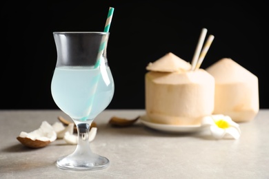 Glass with fresh coconut water on table against black background