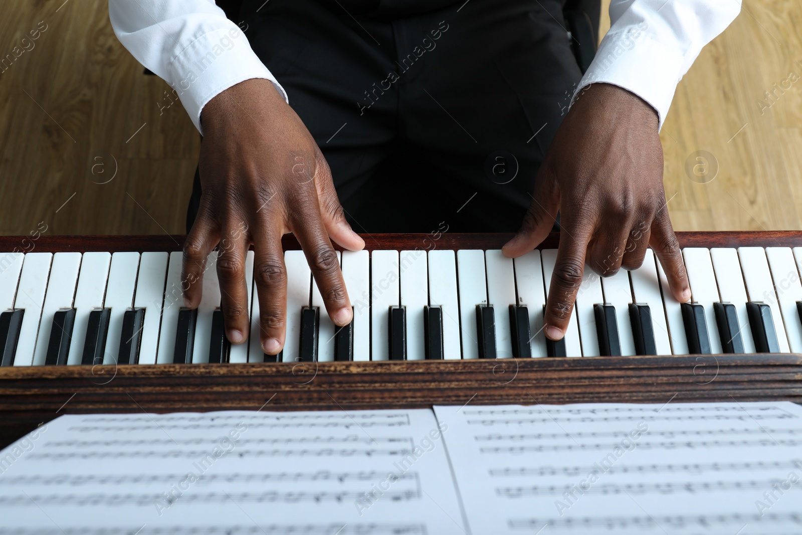 Photo of African-American man playing piano indoors, above view. Talented musician