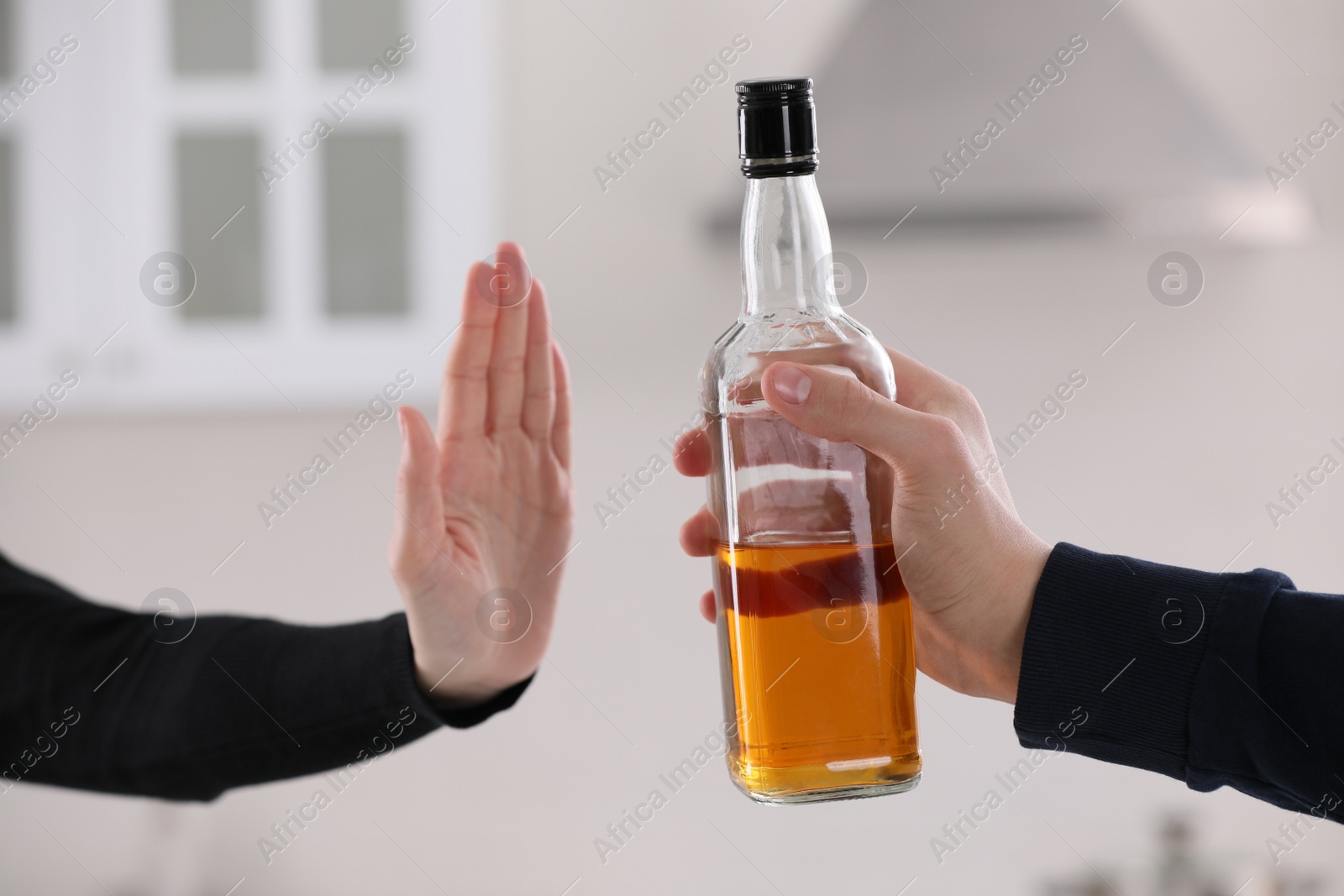 Photo of Woman refusing to drink whiskey in kitchen, closeup. Alcohol addiction treatment