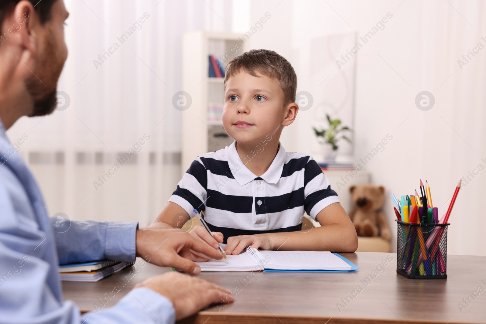 Photo of Dyslexia treatment. Teacher working with boy at table in room