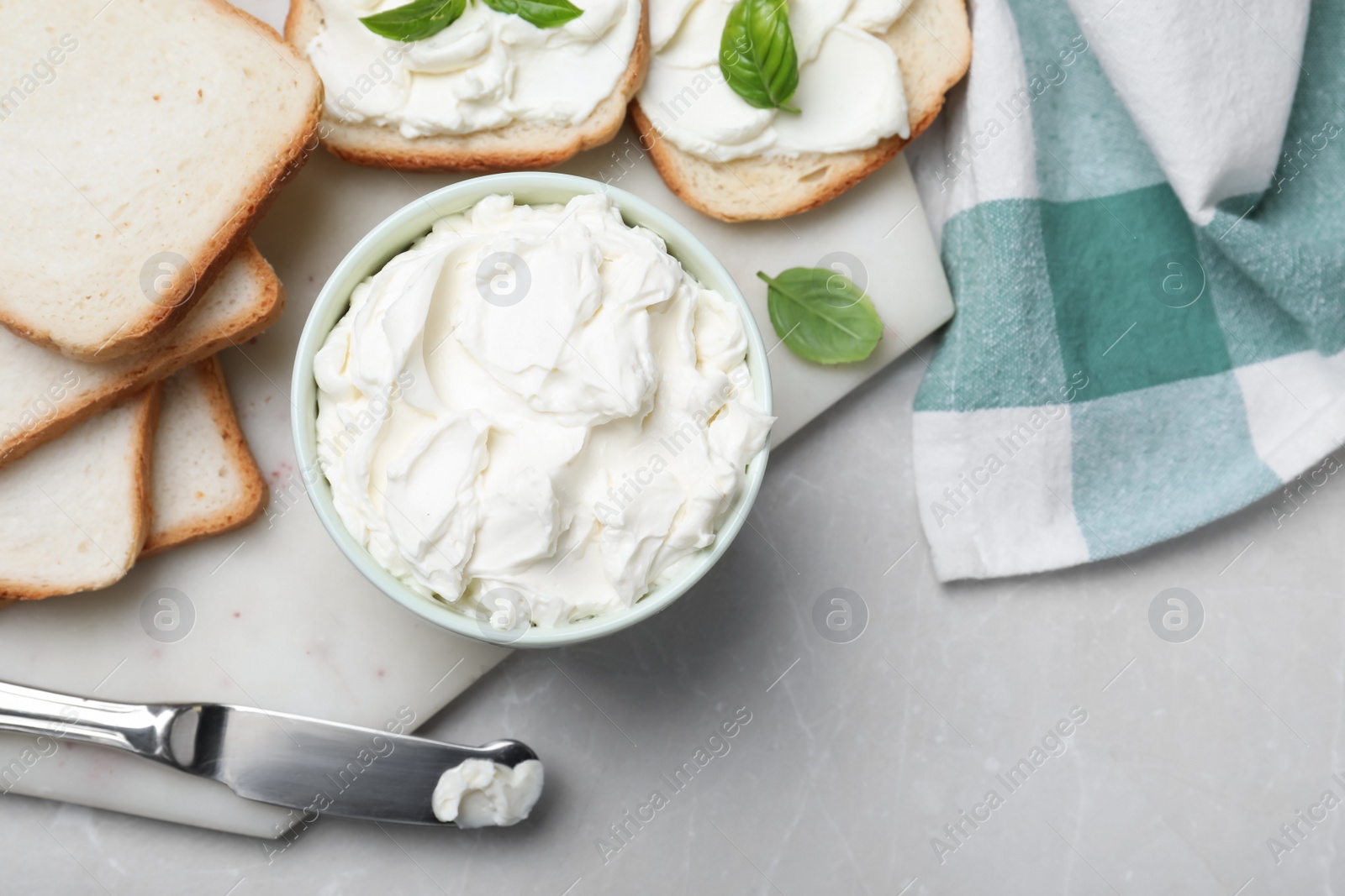 Photo of Fresh bread and delicious cream cheese on grey table, flat lay