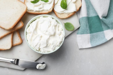 Fresh bread and delicious cream cheese on grey table, flat lay