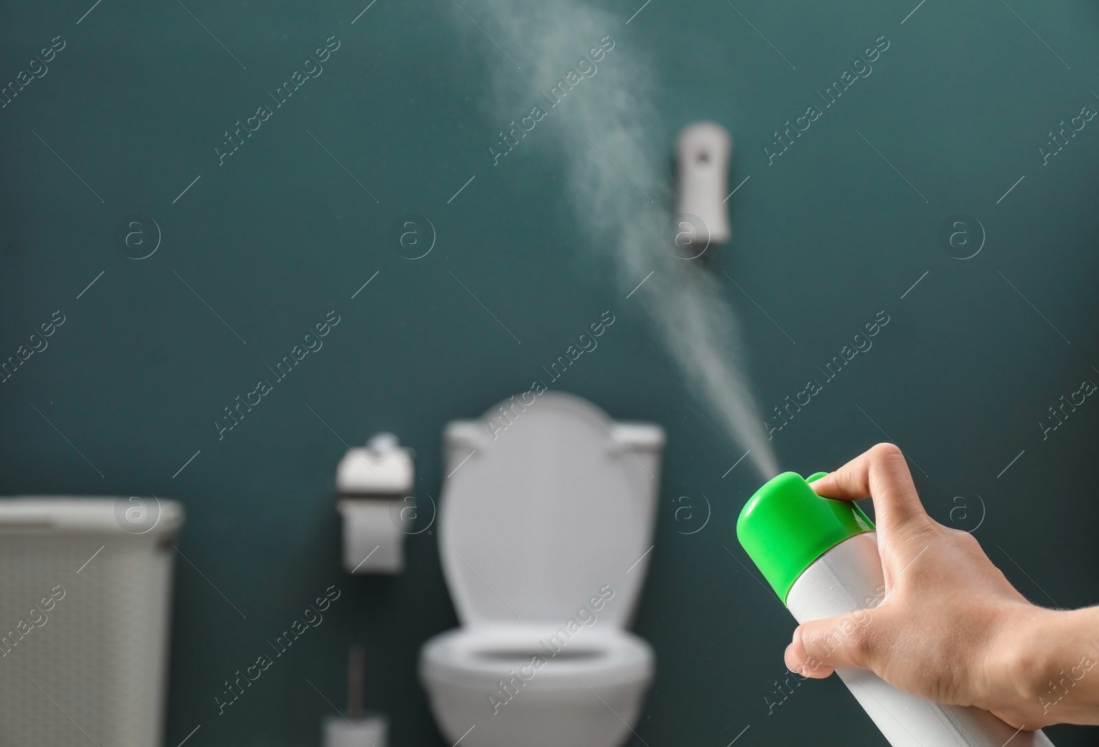 Photo of Woman spraying air freshener in bathroom