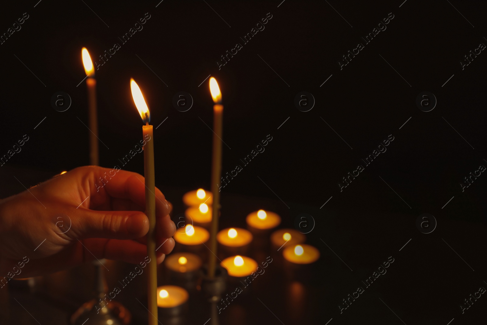 Photo of Young person holding burning candle in darkness, closeup