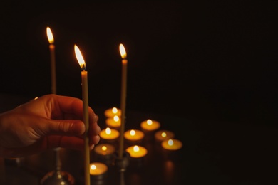 Photo of Young person holding burning candle in darkness, closeup