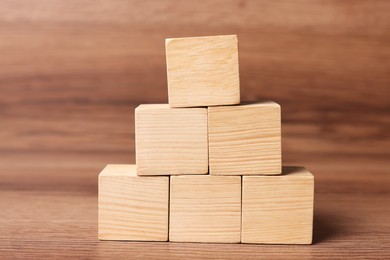 Photo of Pyramid of cubes on wooden background, space for text. Idea concept