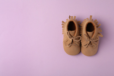 Photo of Child's booties on violet background, flat lay with space for text