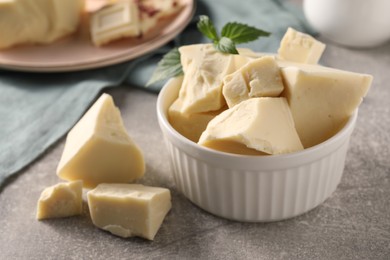 Photo of Pieces of tasty white chocolate on grey table, closeup