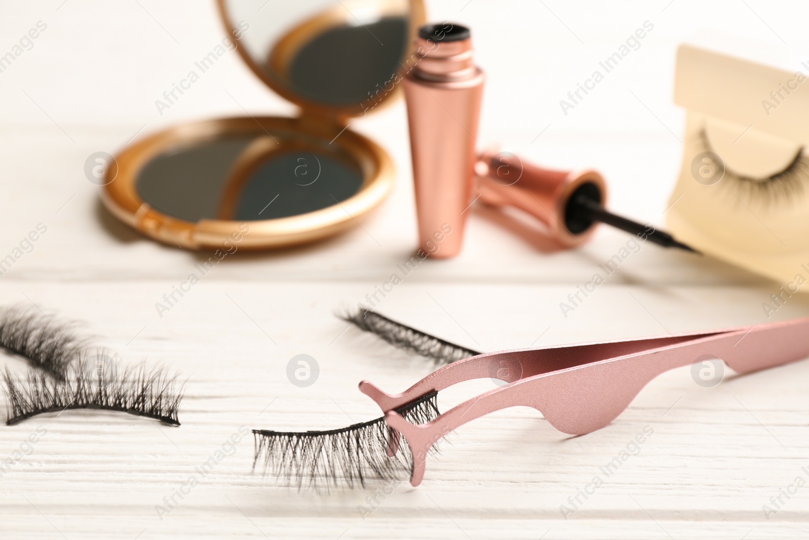 Photo of Magnetic eyelashes and accessories on white wooden table, closeup