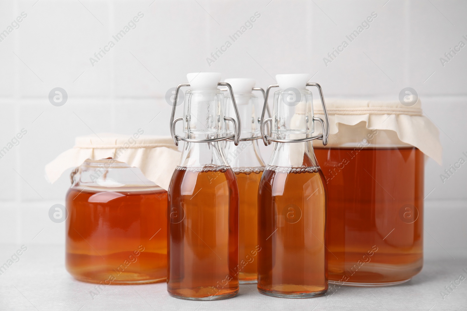 Photo of Tasty kombucha in glass jars and bottles on white table