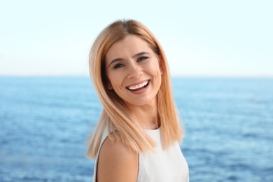 Portrait of beautiful blonde woman near sea