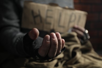 Poor homeless man with help sign begging for money, closeup. Charity and donation