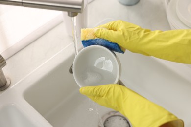 Photo of Woman washing cup at sink in kitchen, closeup