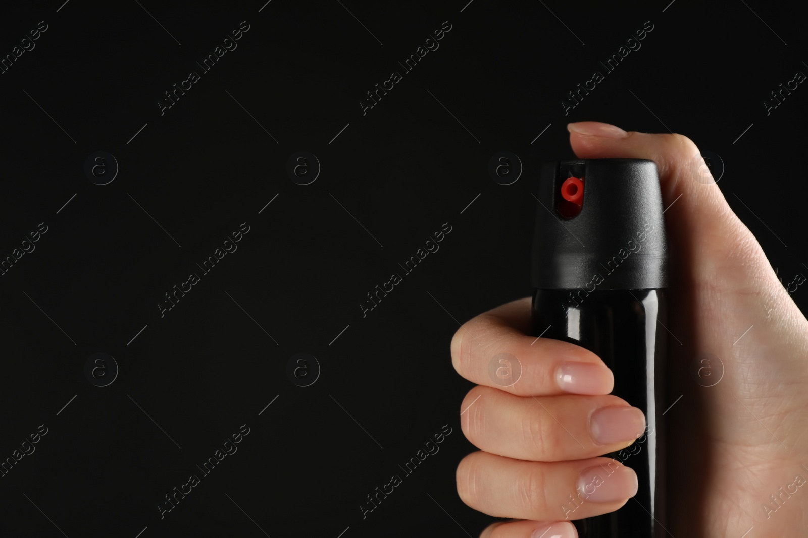 Photo of Woman holding pepper spray on black background, closeup. Space for text