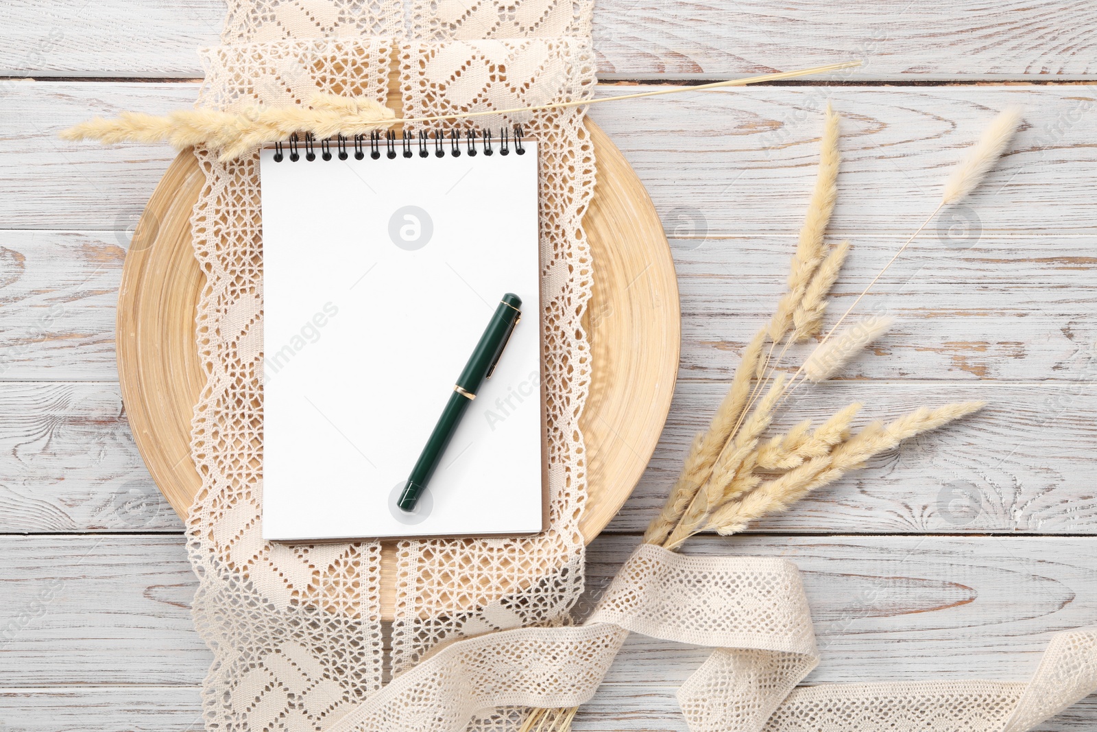 Photo of Guest list. Notebook, pen, spikelets and lace ribbons on wooden background, flat lay