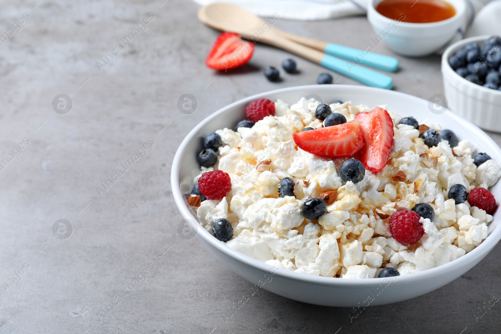 Photo of Delicious cottage cheese with fresh berries served on light grey table, space for text. Tasty breakfast