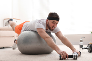 Lazy young man with sport equipment at home