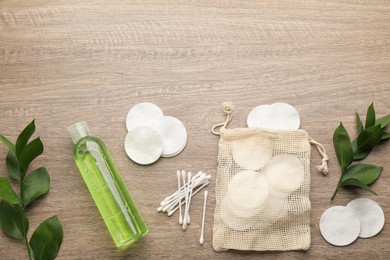 Photo of Cotton pads, swabs and makeup removal product on wooden table, flat lay. Space for text