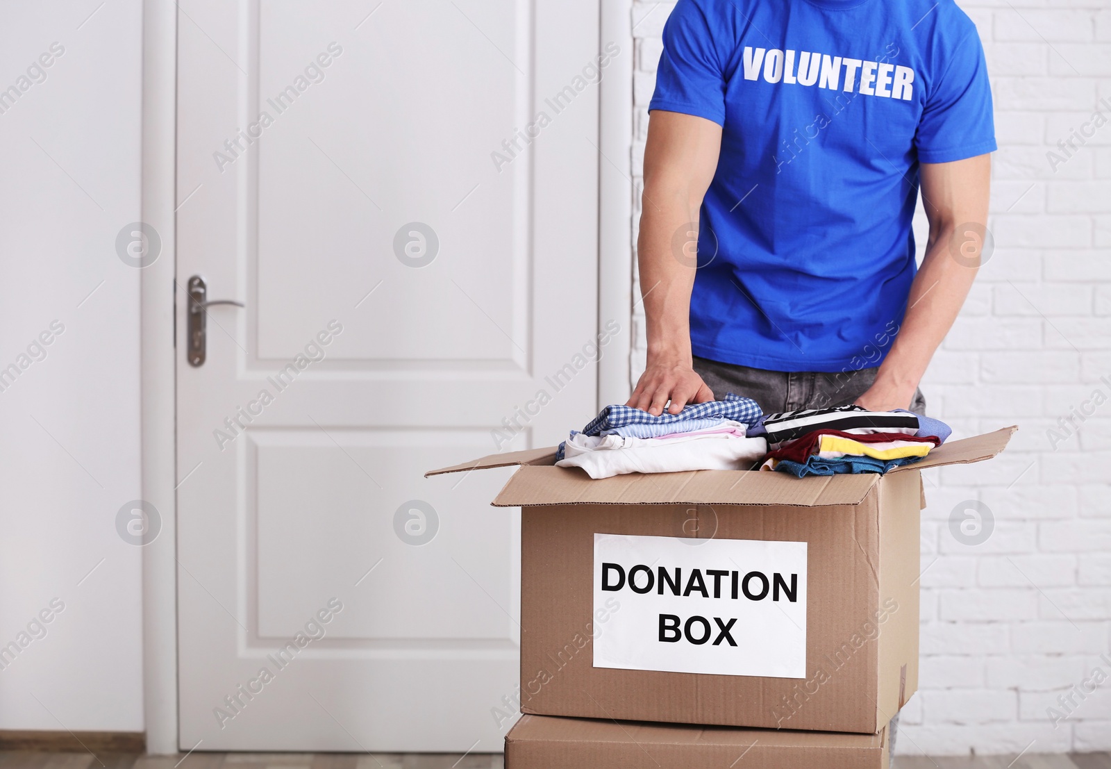 Photo of Male volunteer putting clothes in donation box indoors