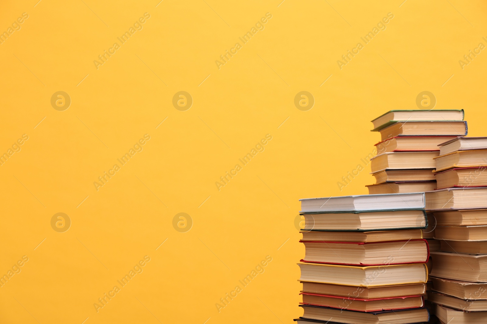 Photo of Many hardcover books on orange background, space for text. Library material