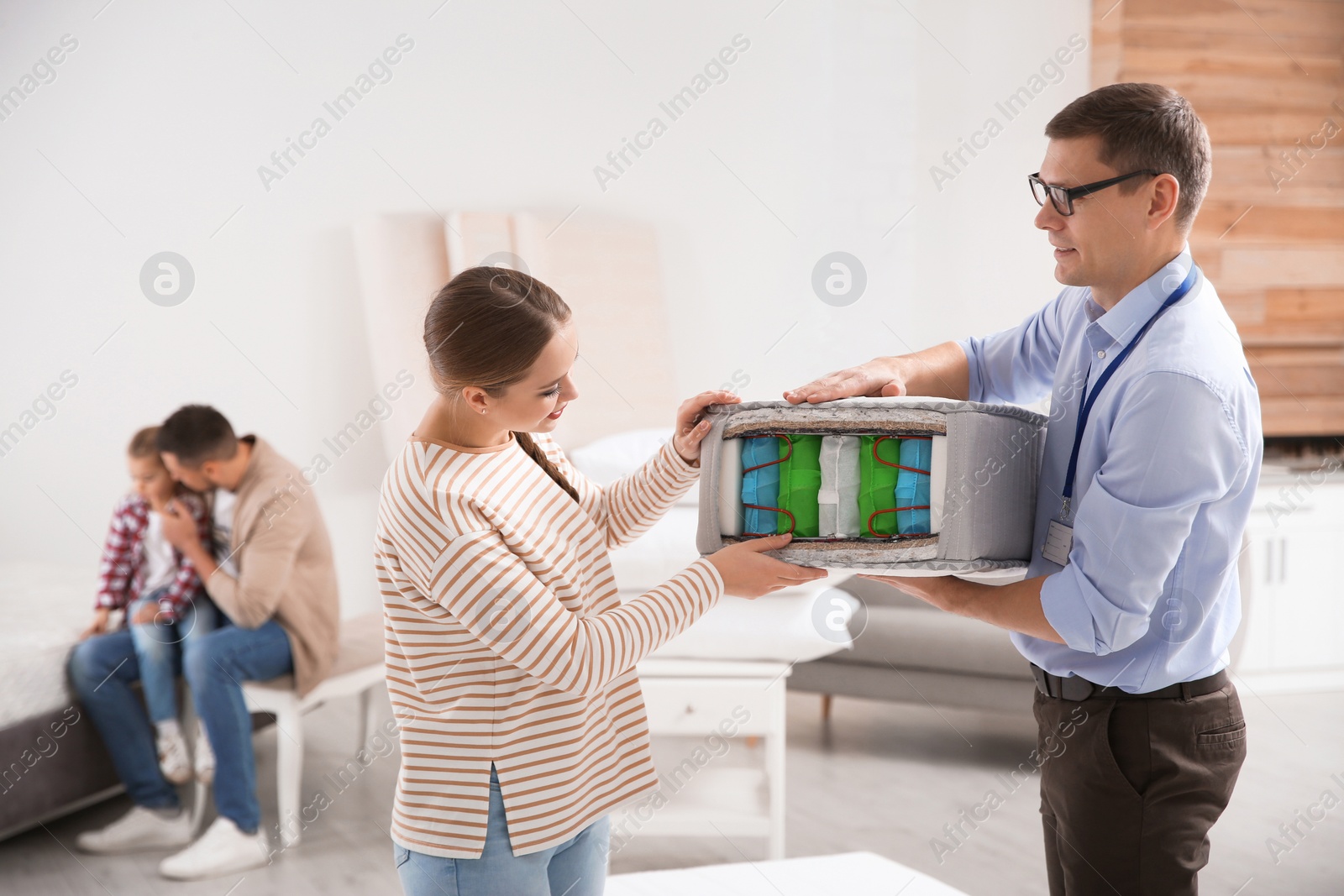 Photo of Salesman showing young woman section of mattress in store