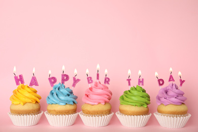 Photo of Birthday cupcakes with burning candles on pink background. Space for text