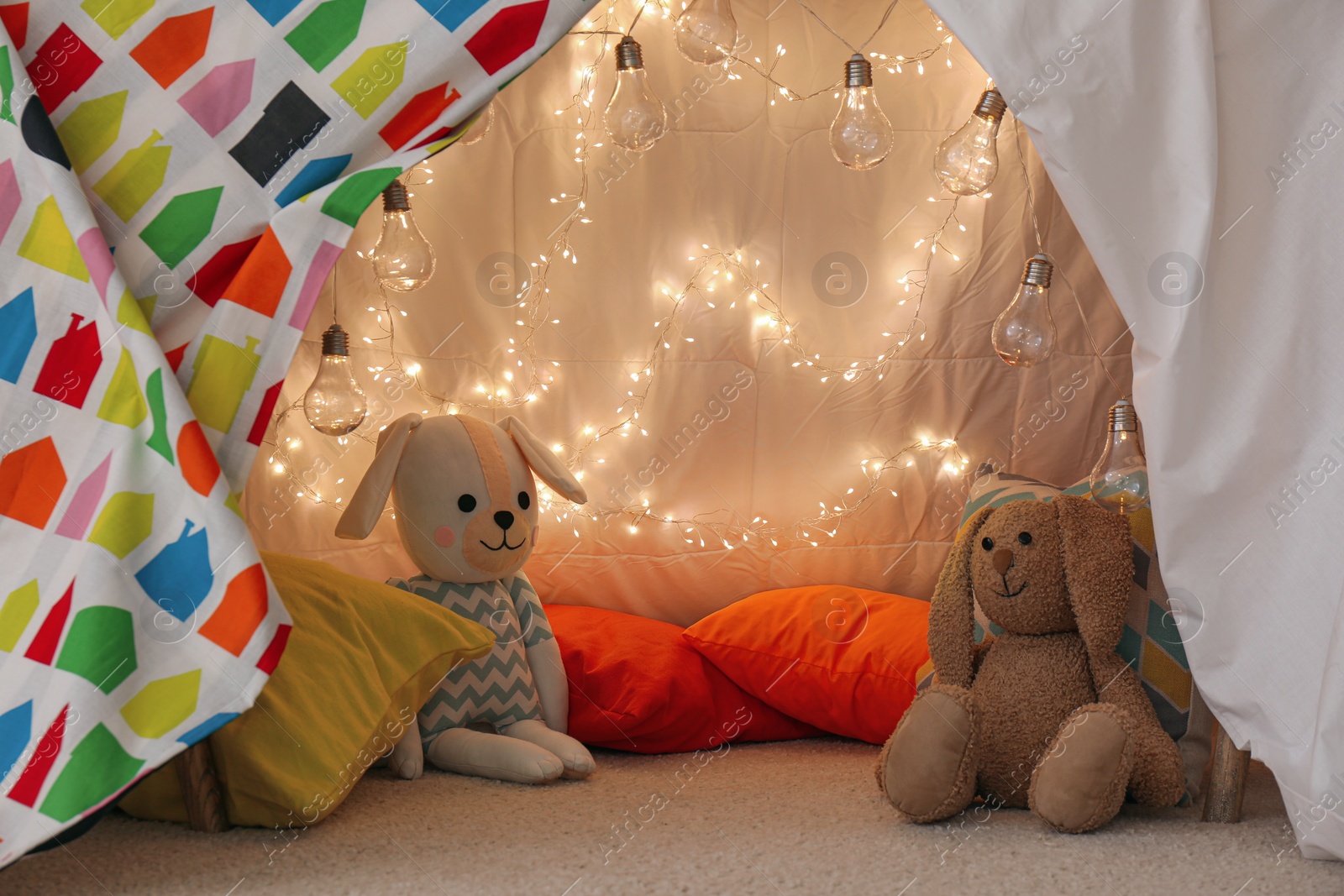 Photo of Play tent with toys and pillows indoors, closeup. Modern children's room interior