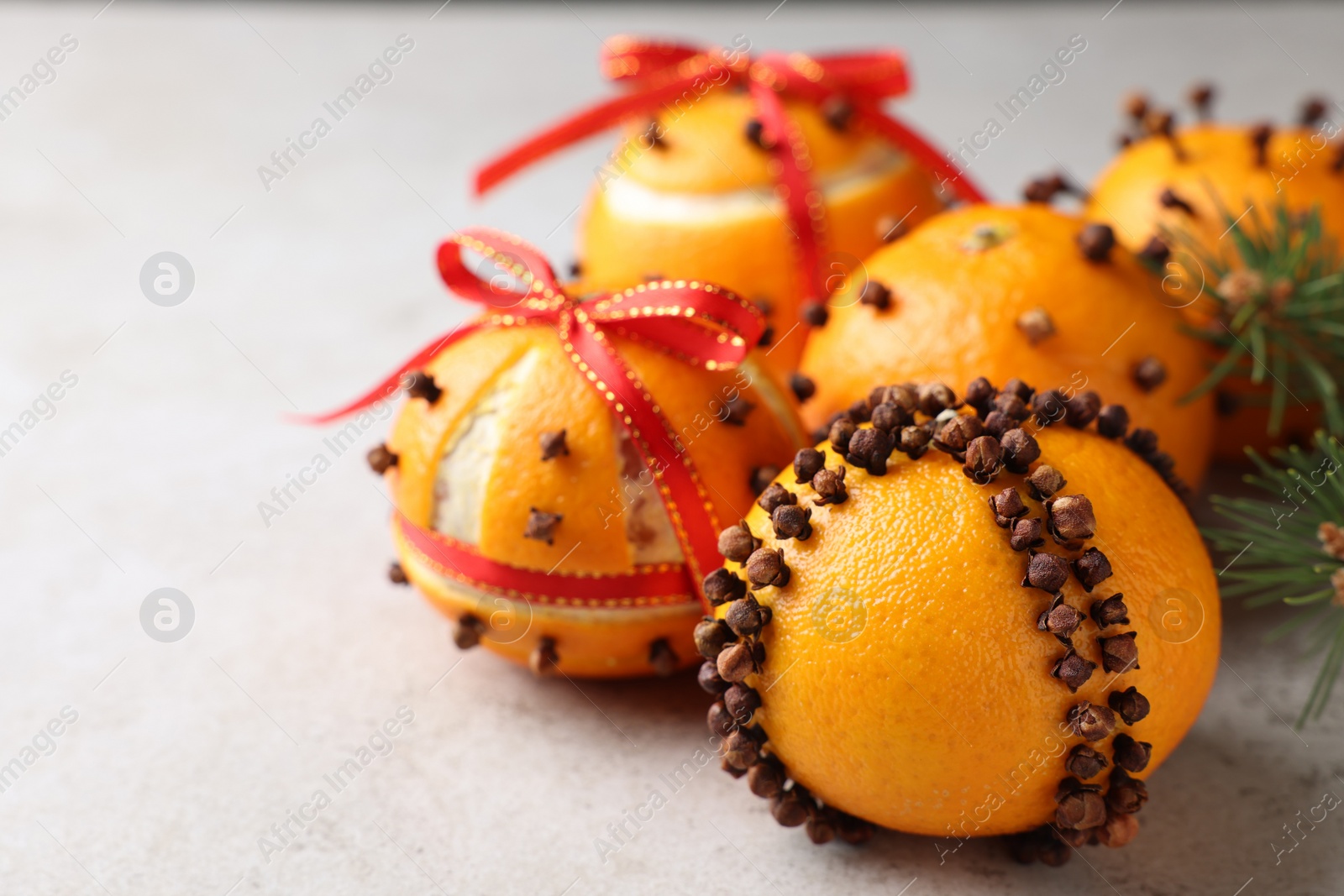 Photo of Pomander balls made of tangerines with cloves on grey table, closeup. Space for text