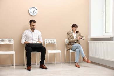 Photo of Man and woman waiting for job interview indoors