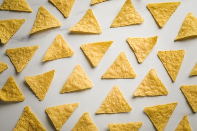 Photo of Flat lay composition of tasty tortilla chips (nachos) on white table