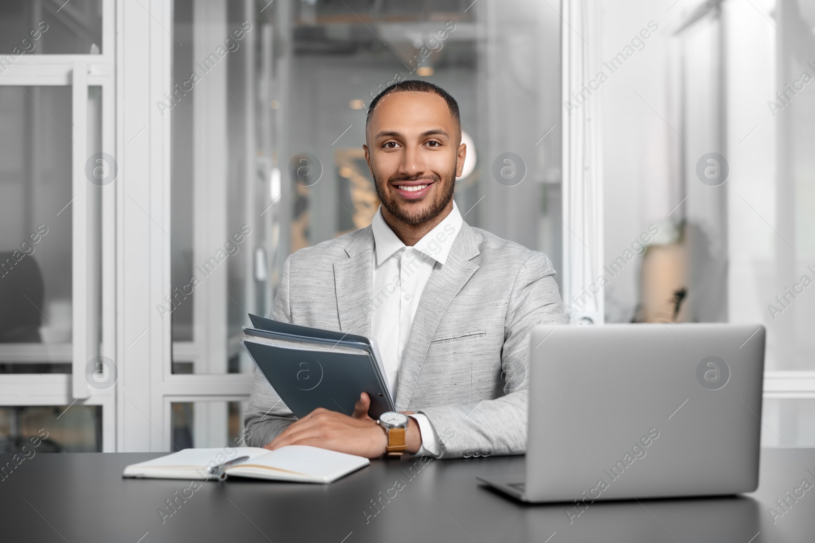 Photo of Happy man with folders working at table in office. Lawyer, businessman, accountant or manager