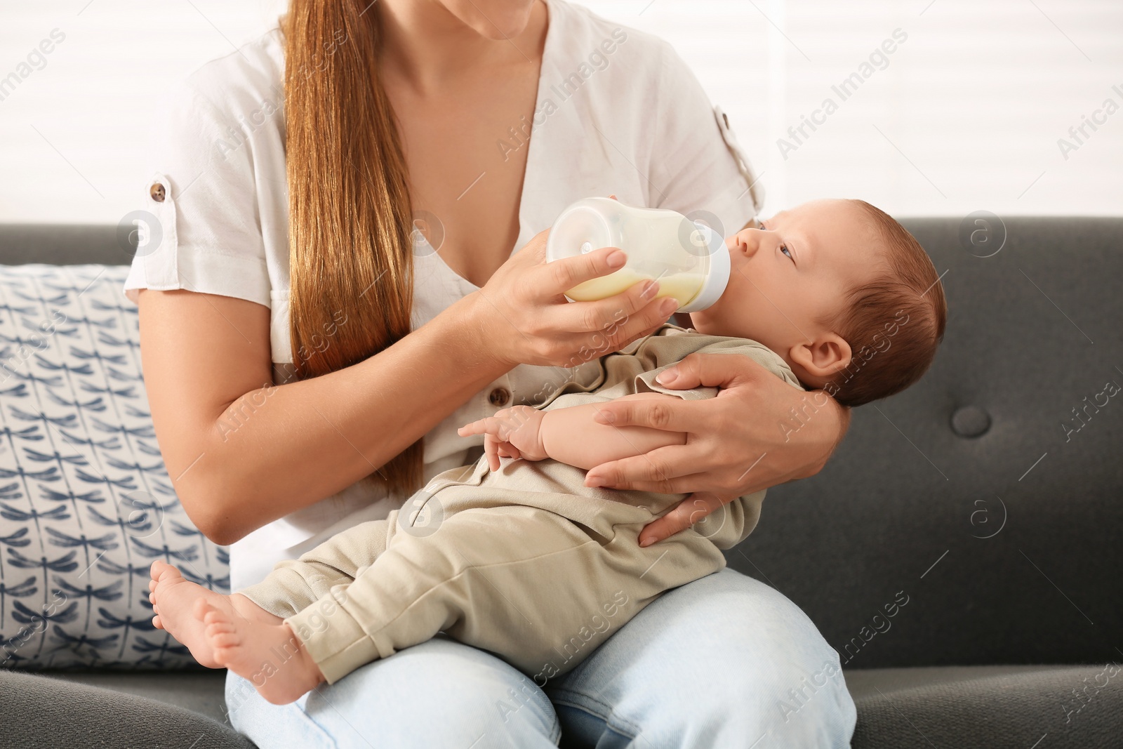 Photo of Mother feeding her cute child with infant formula indoors