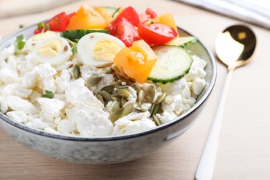 Photo of Fresh cottage cheese with vegetables, seeds and eggs in bowl on wooden table, closeup