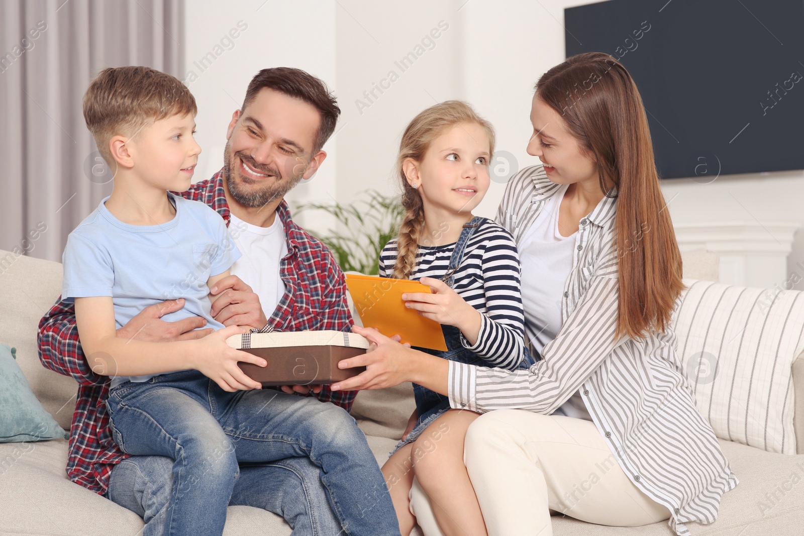 Photo of Happy family presenting each other with gifts on sofa at home