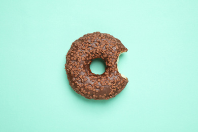 Photo of Delicious glazed donut on turquoise background, top view