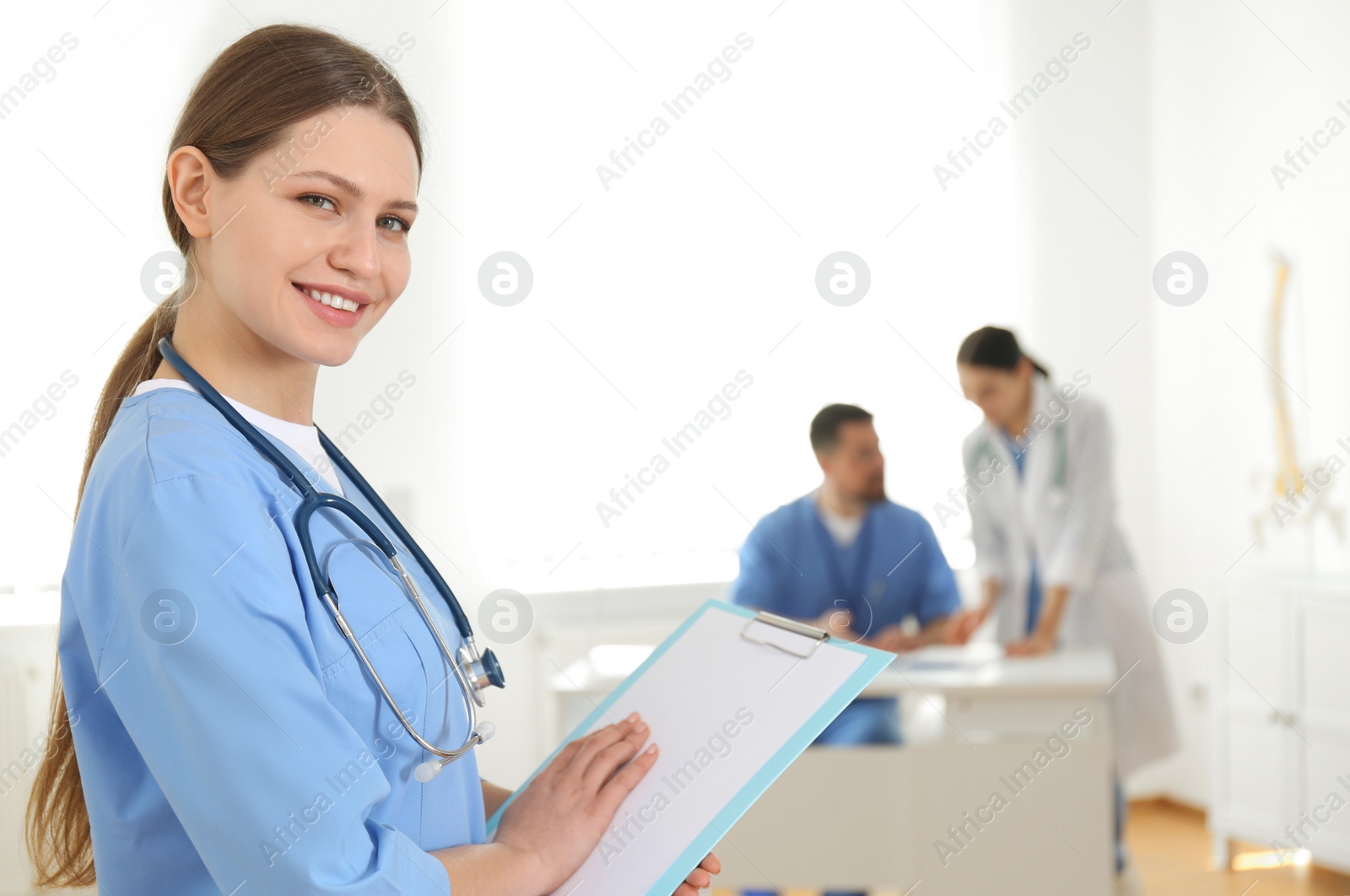 Photo of Portrait of young doctor with clipboard in hospital, space for text. Medical service