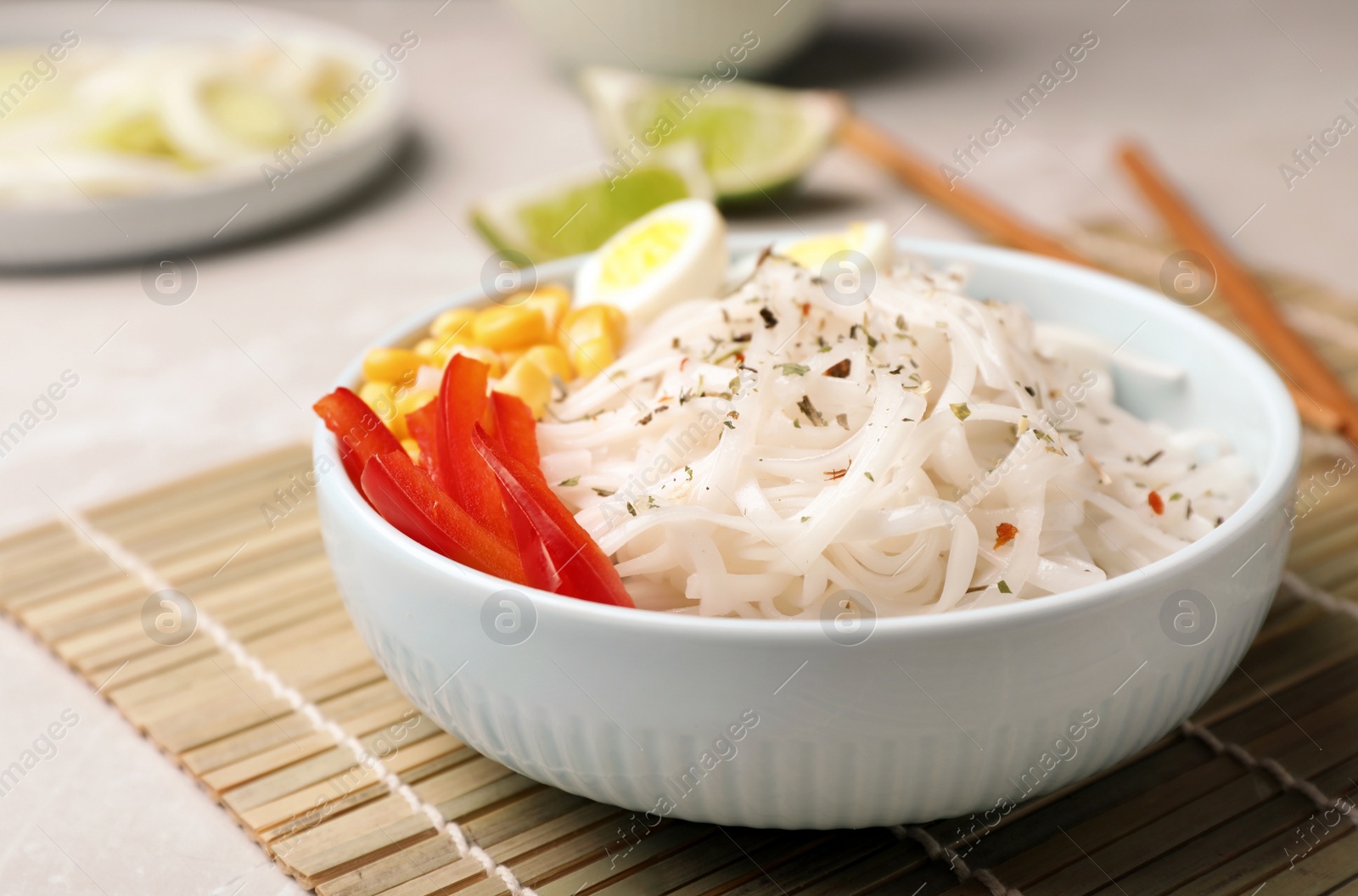 Photo of Bowl with rice noodles and vegetables on table