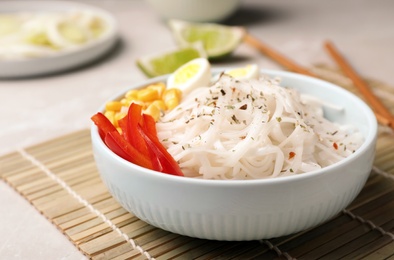 Photo of Bowl with rice noodles and vegetables on table