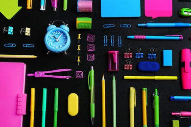 Photo of Different bright school stationery on black background, flat lay