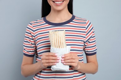 Photo of Young woman with delicious shawarma on grey background, closeup
