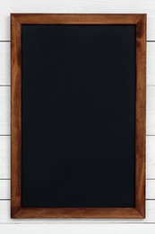 Clean black chalkboard hanging on white wooden wall