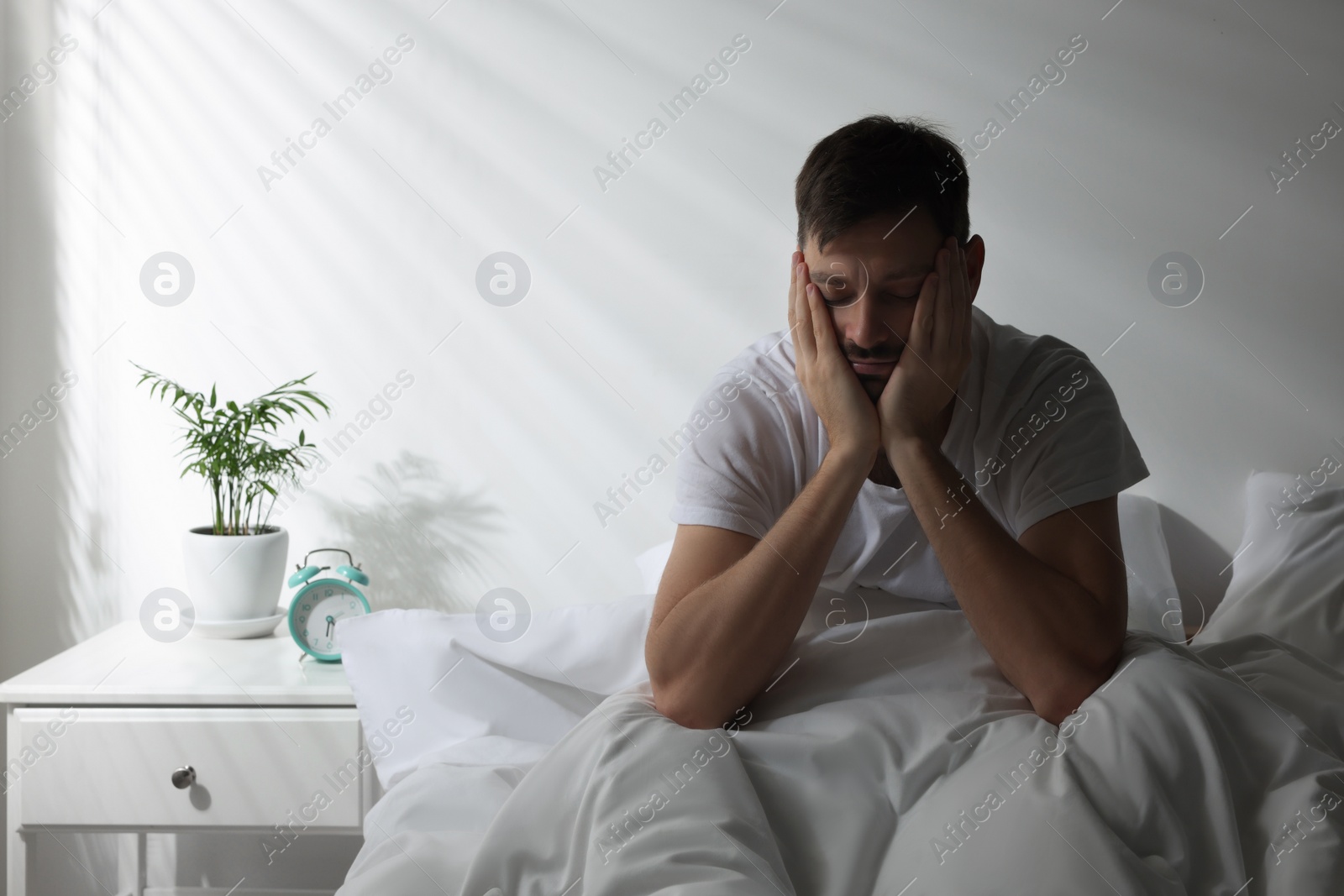 Photo of Sleepy man sitting in bed at home