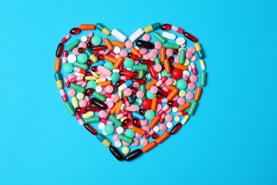 Photo of Heart made of pills on color background, top view