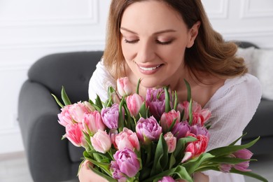 Young woman with bouquet of beautiful tulips indoors