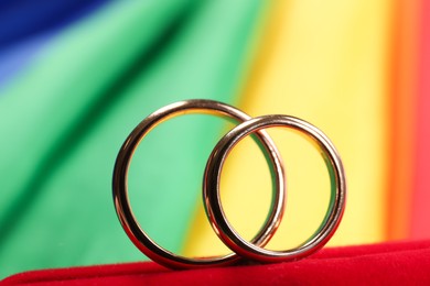 Wedding rings on rainbow LGBT flag, closeup