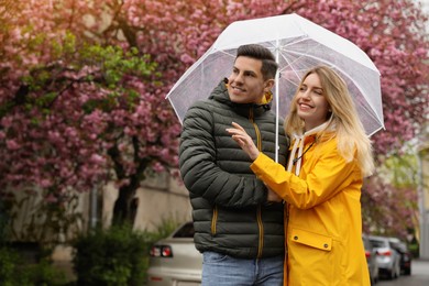 Photo of Lovely couple with umbrella walking on spring day
