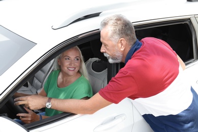 Senior man teaching his wife to drive car. Loving couple on road trip