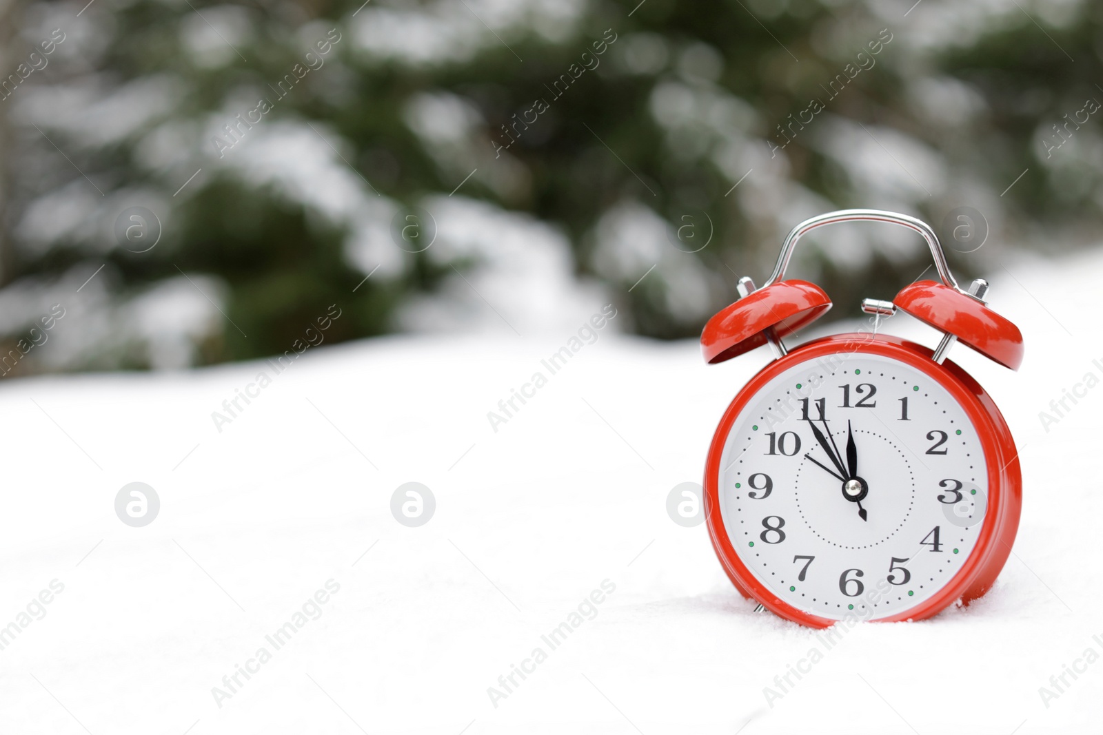 Photo of Red alarm clock on white snow outdoors. Space for text