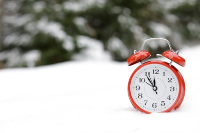 Photo of Red alarm clock on white snow outdoors. Space for text